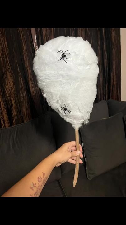 a person holding a large white pillow with spider on it's head in front of a black couch