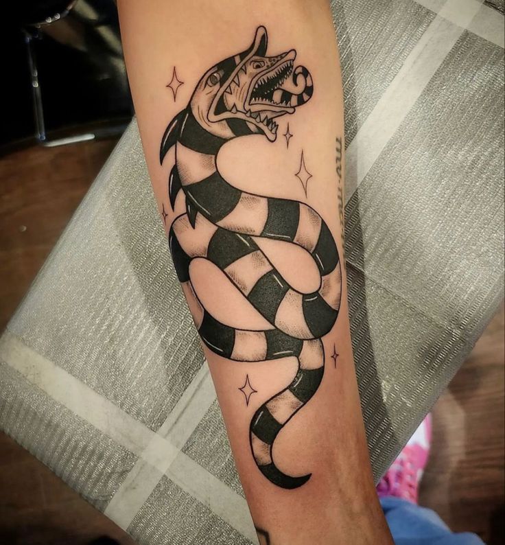 a black and white snake tattoo on the right arm, with stars around it's neck