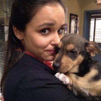 a woman holding a small dog in her arms and looking at the camera with an angry look on her face