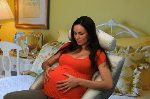 a pregnant woman sitting in a chair holding her stomach