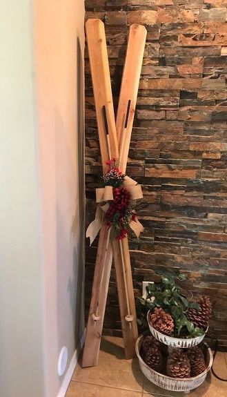 two wooden skis leaning up against a wall with pine cones in the bottom basket