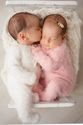 two newborn babies are cuddling in a white box with their heads touching each other