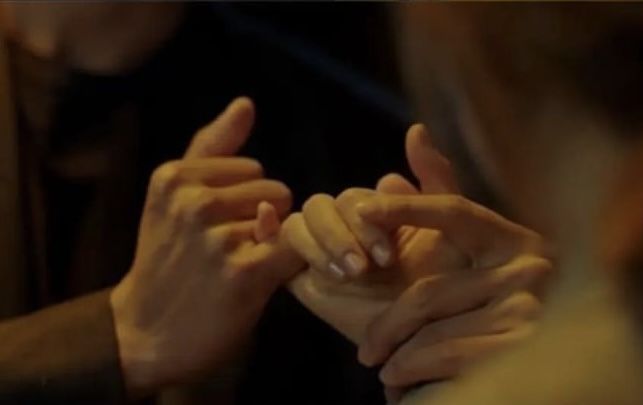 two people holding hands in the dark with their fingers touching each other's palms