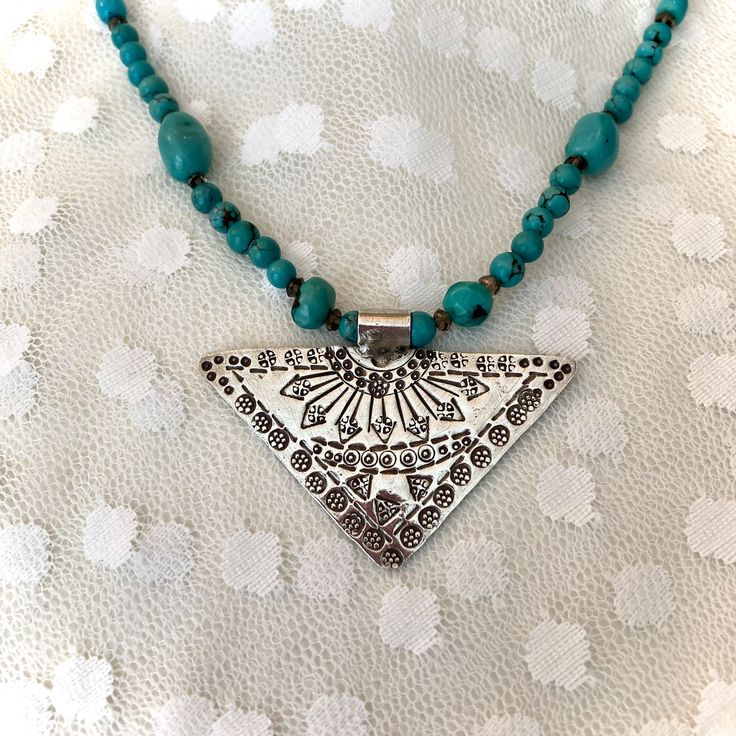 This 18 inch turquoise boho chic tribal necklace features turquoise and smokey topaz gemstones with a hand stamped Hill Tribe silver pendant triangular in shape. This striking pendant, intricately hand made and stamped by the Hill Tribe women artisans of Thailand to support their families, measures over 2 inches at its widest point and hangs gracefully from the necklace. Hill Tribe silver is 97.5 to 99 % pure silver. The turquoise stones are rich in color with a slight black matrix, varying in s Spiritual Turquoise Necklace For Festivals, Spiritual Turquoise Pendant Necklace For Festival, Artisan Adjustable Turquoise Pendant Necklace, Bohemian Beaded Necklace With Oxidized Finish As Gift, Nickel Free Bohemian Necklace For Festivals, Adjustable One-of-a-kind Turquoise Necklace For Festivals, Bohemian Nickel-free Necklace For Festivals, Silver Bohemian Beaded Necklaces, Nickel-free Bohemian Necklace For Festival