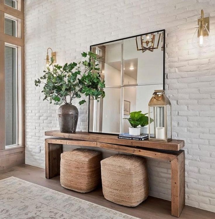 a white brick wall with a mirror, plant and stools in front of it