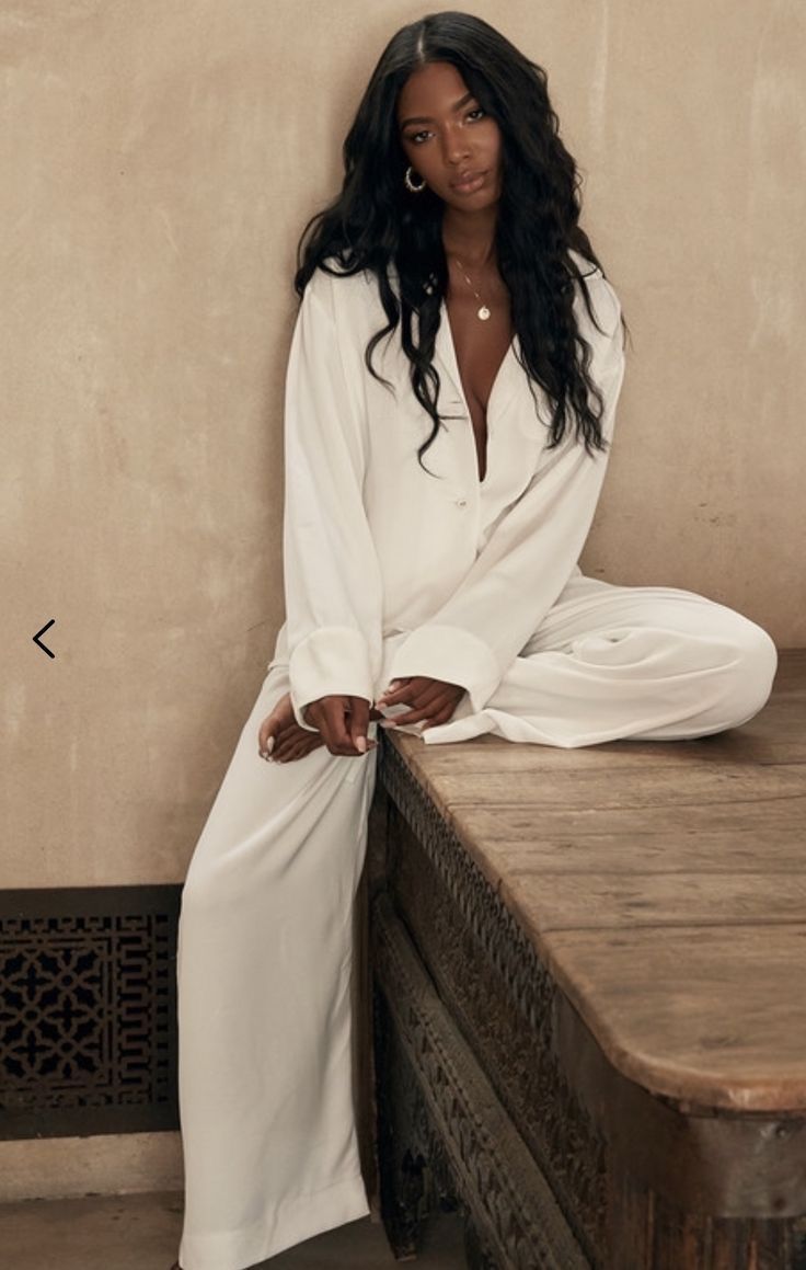 a woman sitting on top of a wooden table next to a white shirt and pants