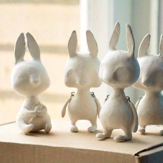 four little white rabbits sitting on top of a cardboard box