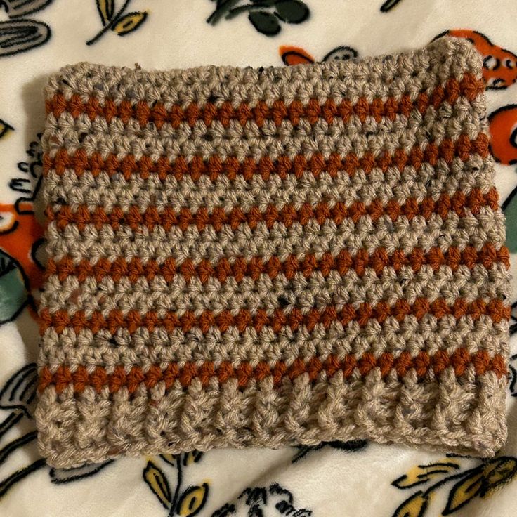 an orange and white striped crochet dishcloth on a floral print table cloth