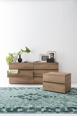 a living room with a large rug and wooden furniture on the floor in front of a white wall