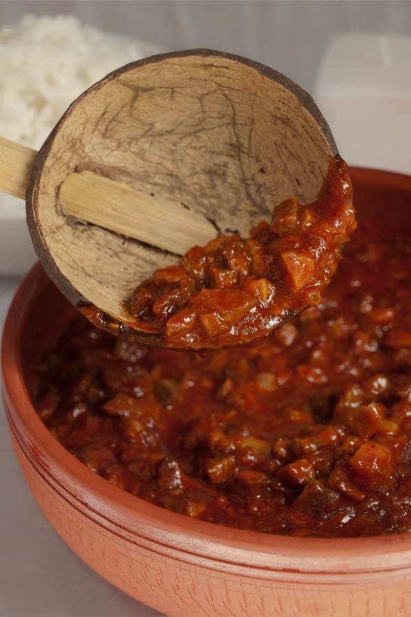 a wooden spoon full of chili and rice