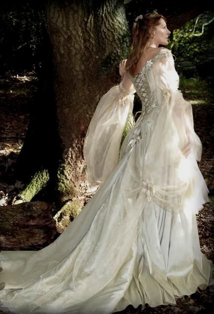 a woman in a white dress standing next to a tree