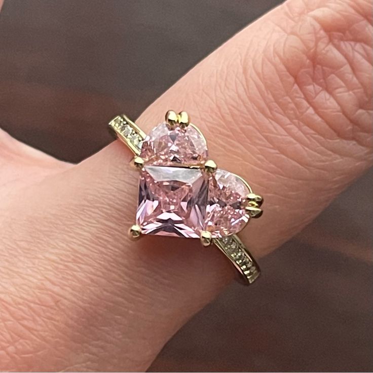 a woman's hand with a pink diamond ring on it