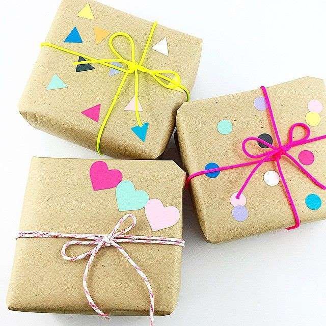 three wrapped gift boxes with hearts and confetti on them, tied with twine