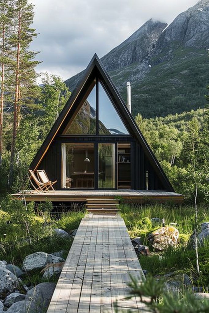 a wooden walkway leading to a small cabin in the woods with mountains in the background