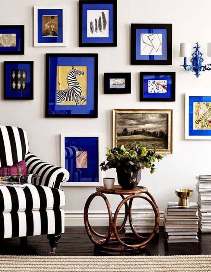 a living room with black and white striped furniture, blue framed pictures on the wall