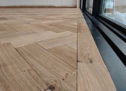 an empty room with wood flooring next to a window