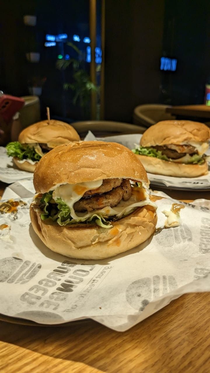 two hamburgers sitting on top of paper on a table