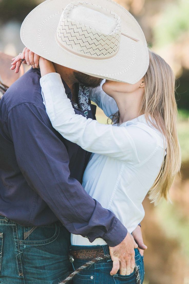 a man and woman kissing each other while wearing cowboy hats