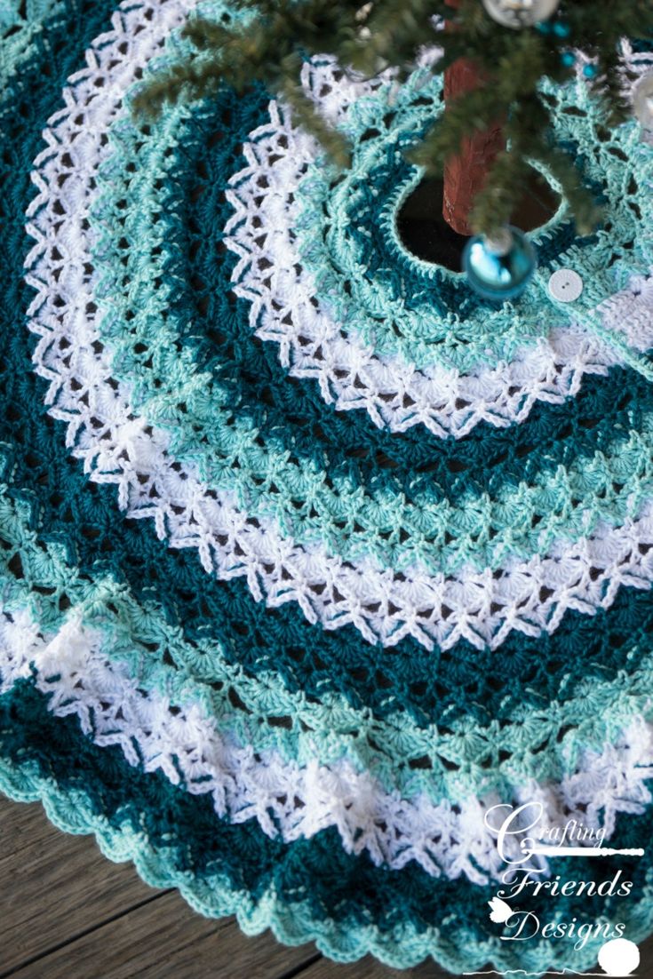 a crocheted christmas tree skirt is shown on a wooden table with a pine tree in the center