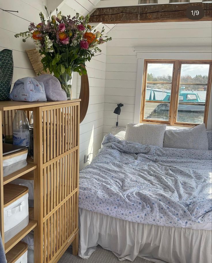 a bed sitting next to a window in a bedroom on top of a wooden floor