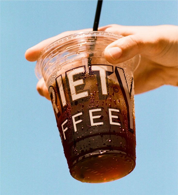 a person holding a plastic cup with a straw in it that says let's coffee