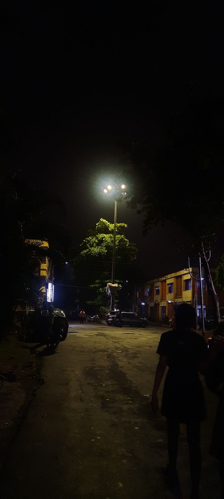 two people walking down a dark street at night