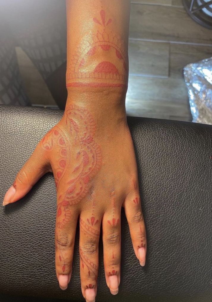 a woman's hand with red and orange tattoos on her left arm, next to a black chair