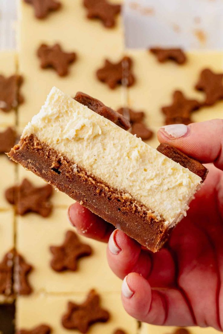 a hand holding a piece of cake with white frosting and chocolate stars on it