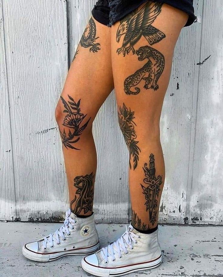 a person with tattoos on their legs standing next to a wall