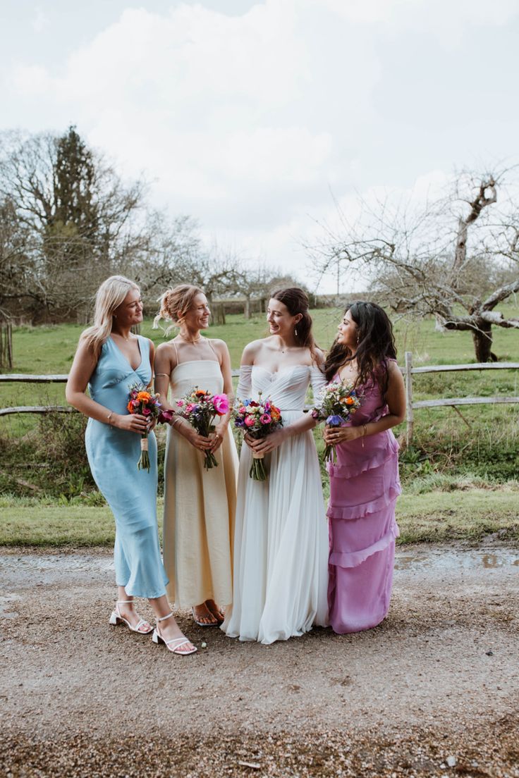 four bridesmaids standing together in front of a fence