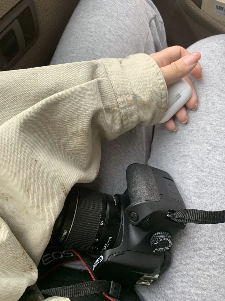 a person sitting in the back seat of a car holding a camera and remote control