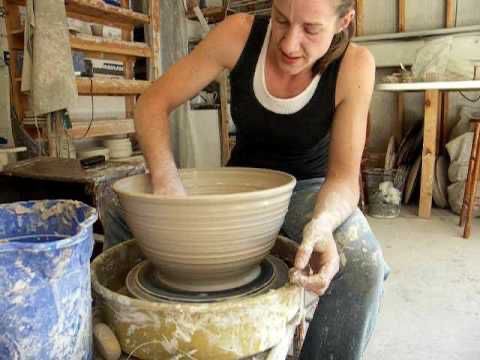 a woman is making a bowl out of clay