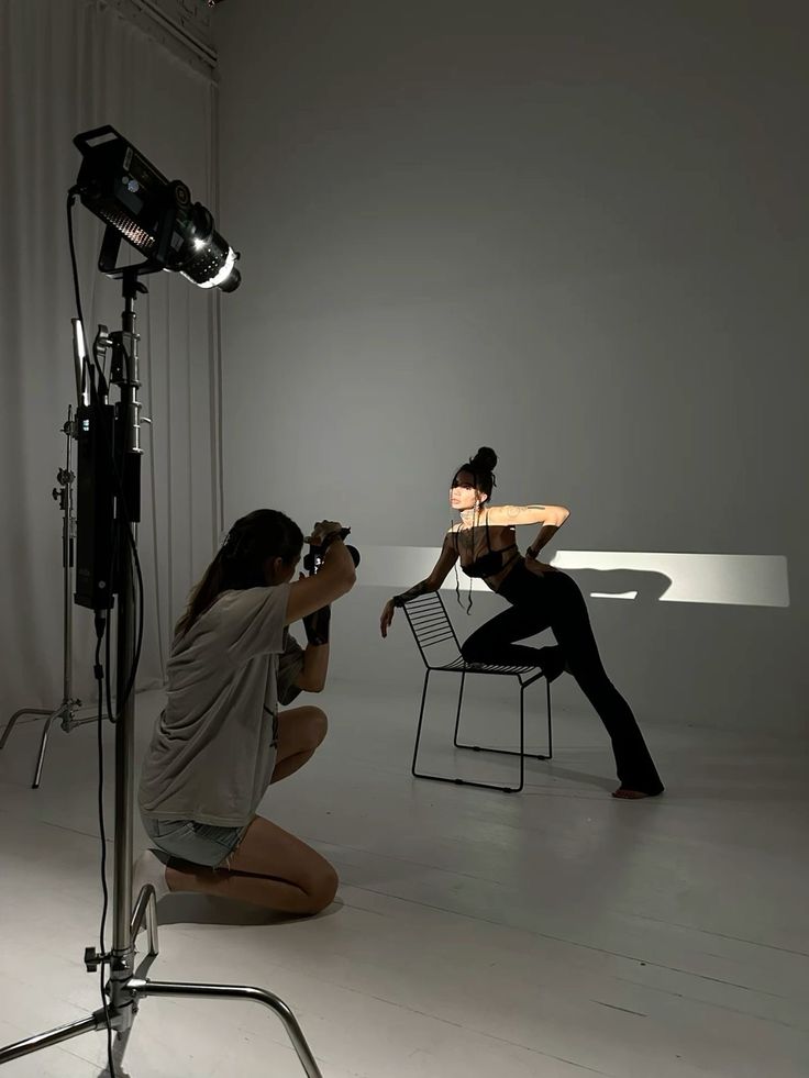 two women sitting on chairs in front of a camera set up for a photo shoot