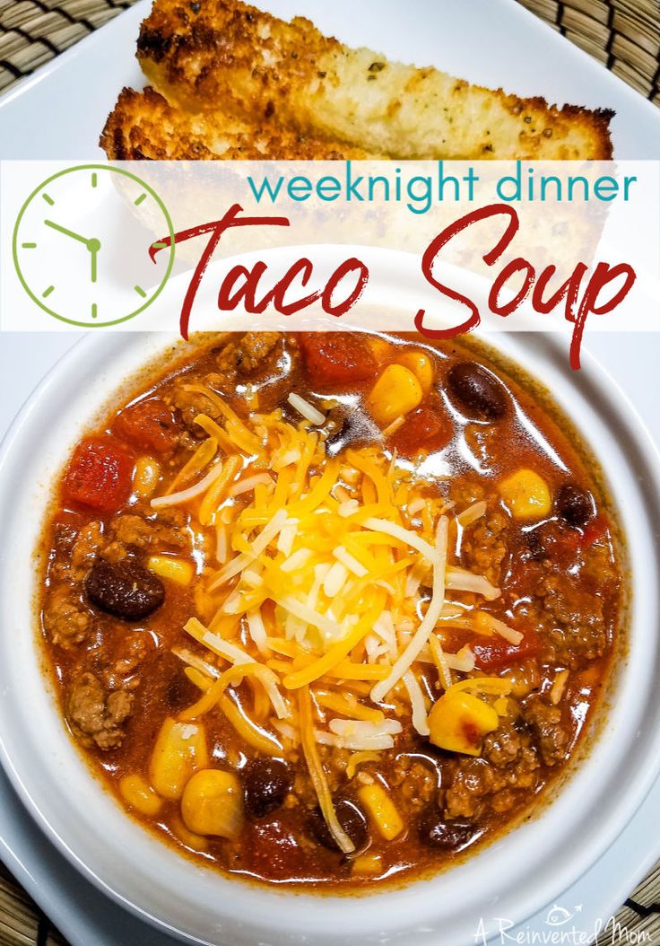 a white bowl filled with taco soup next to a piece of bread on top of a table