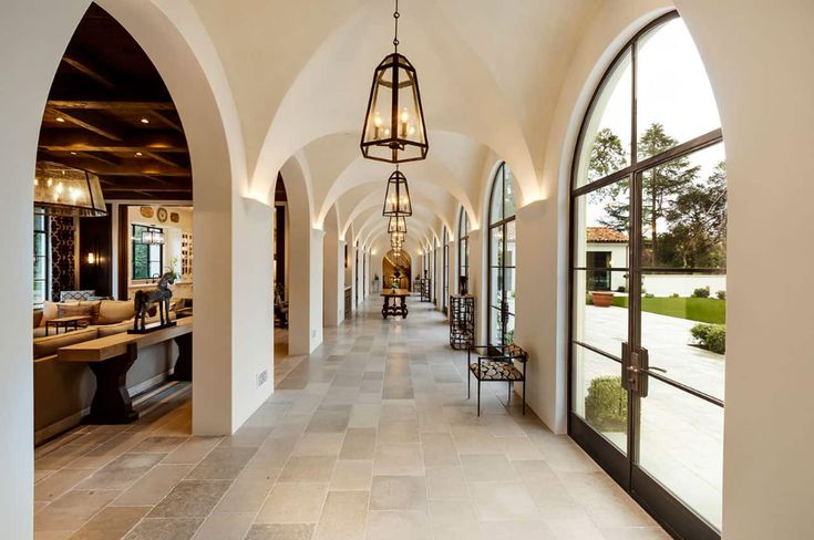 the hallway is lined with arched windows and chandeliers, along with large stone floor tiles