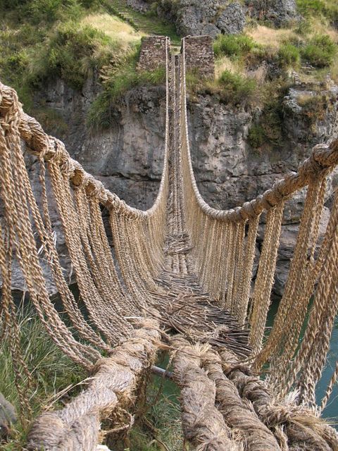 a rope bridge that is next to some water