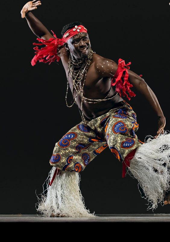 a man is dancing with feathers on his head and body, while wearing an elaborate costume