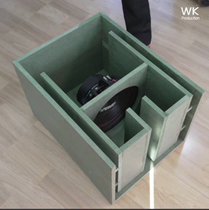 a green box with two doors open on top of a wooden floor next to a person