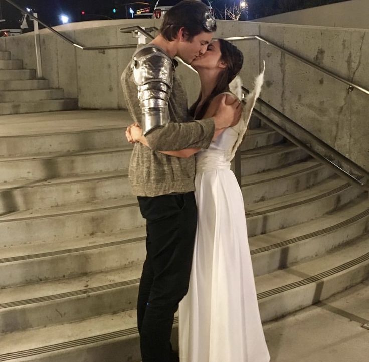 a man and woman dressed in knight costumes kissing on the steps with their arms around each other