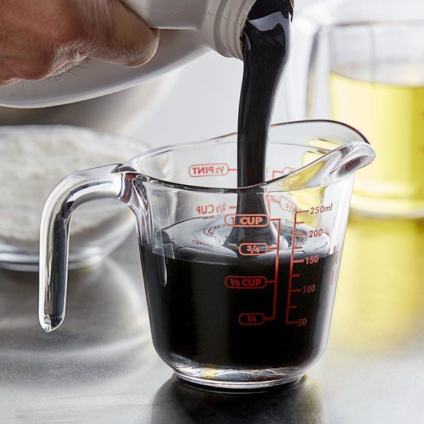 a person pouring liquid into a measuring cup