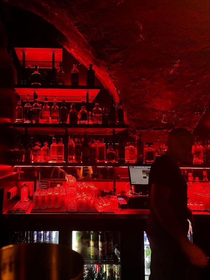 a man standing in front of a bar filled with bottles