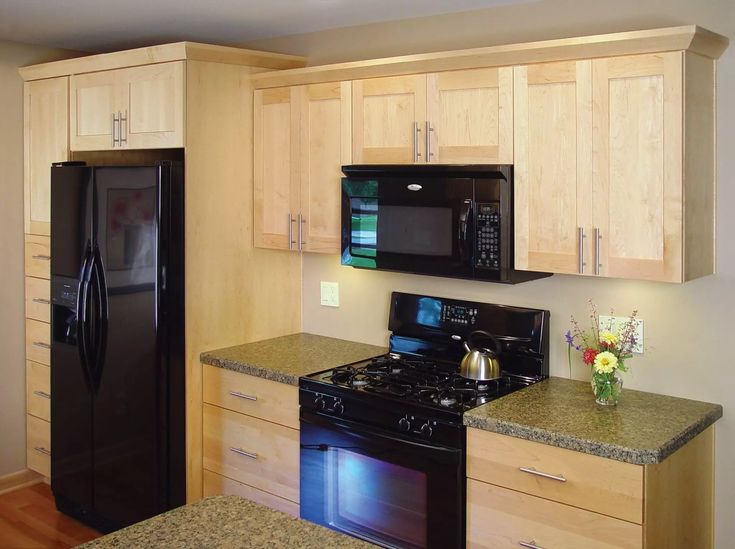 a black refrigerator freezer sitting inside of a kitchen next to a stove top oven