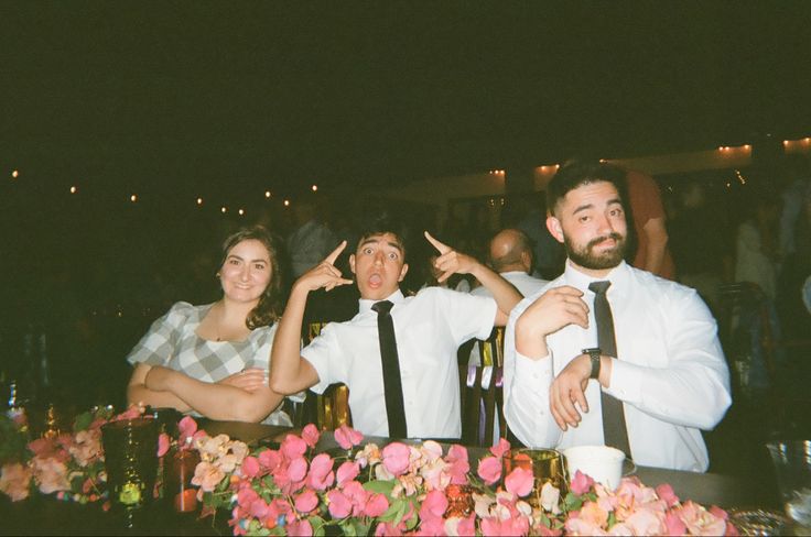 two men and a woman sitting at a table with wine bottles in front of them