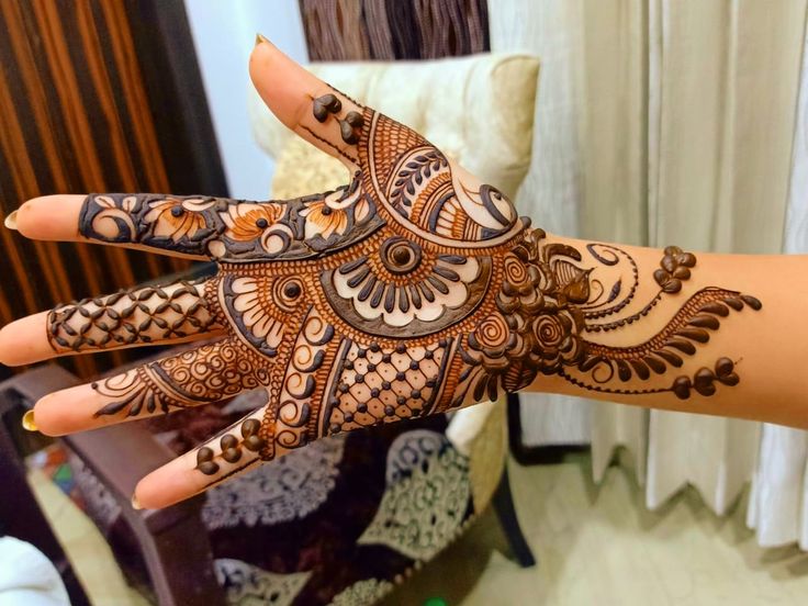 a woman's hand with henna on it, showing the intricate pattern and design