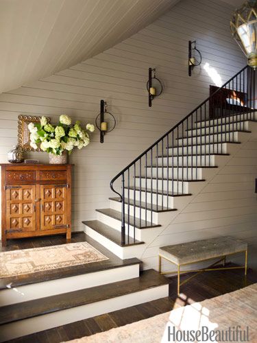 a living room filled with furniture and a stair case in front of a white wall