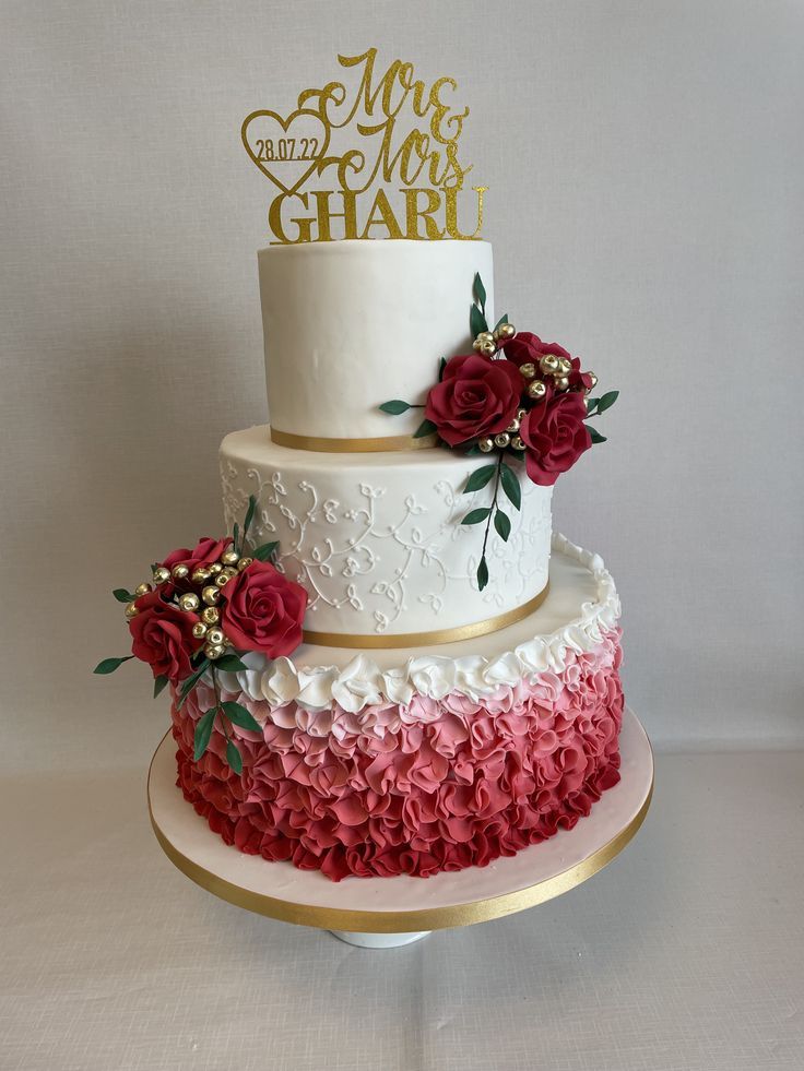 a three tiered wedding cake with red flowers on the bottom and gold lettering that says mr and mrs ghairi