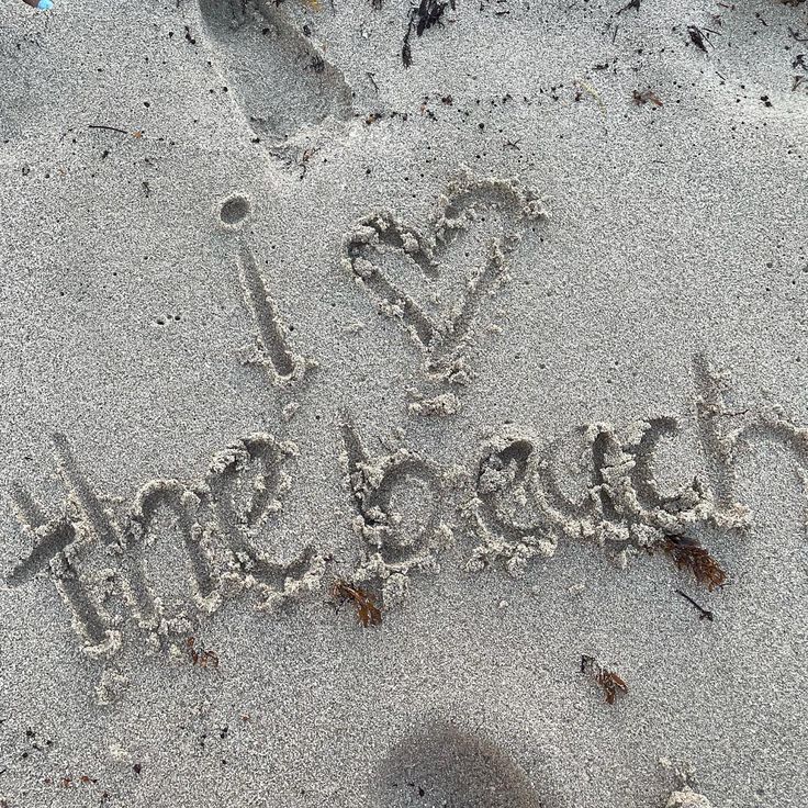 there is a word written in the sand with a heart and arrow drawn on it