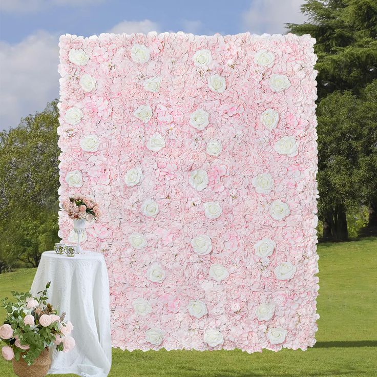 a large pink and white flowered wall next to a table with flowers on it