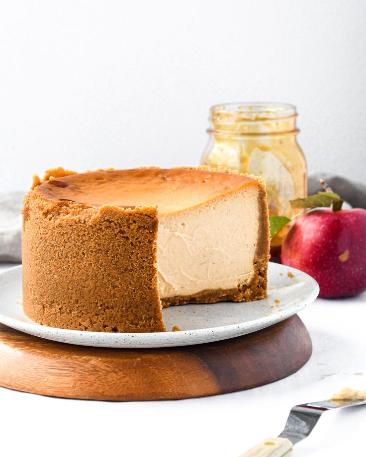 a slice of cheesecake on a plate with an apple in the background