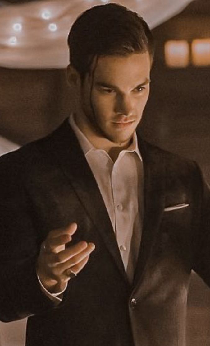 a man in a tuxedo is holding his hand out and looking at something